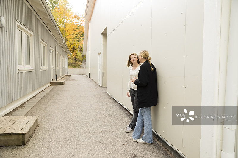 朋友们在通道的墙边站着聊天图片素材