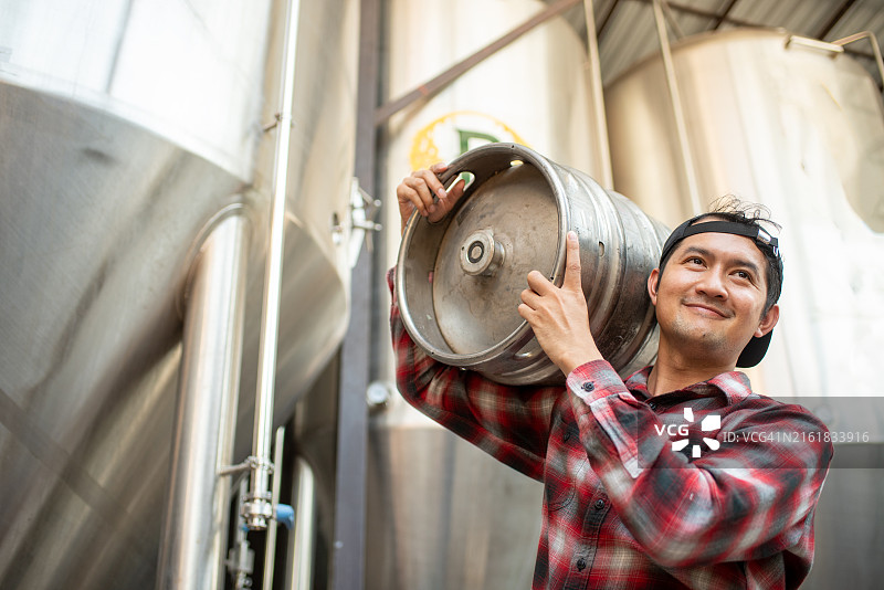 年轻的男性啤酒酿造商拿着一桶啤酒图片素材