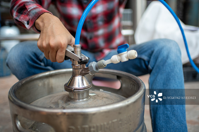 男子在小型啤酒厂清洁啤酒桶图片素材