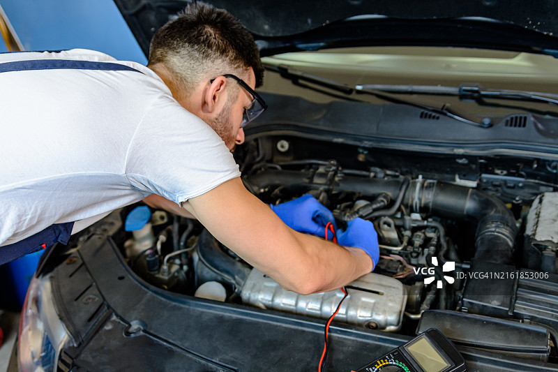 汽车修理工正在修理车间里汽车的电路图片素材