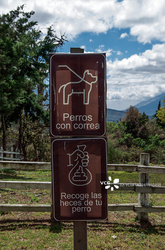 乡村社区中的西班牙语标志：“遛狗请拴绳”和“请清理狗的粪便”图片素材
