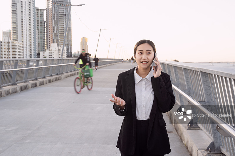 年轻的女商人穿着西装，在去办公室的路上打电话图片素材