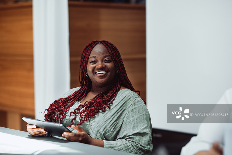 微笑的女人在明亮的现代空间里拿着平板电脑图片素材
