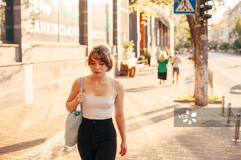 年轻女人在夏天走在城市街道上图片素材
