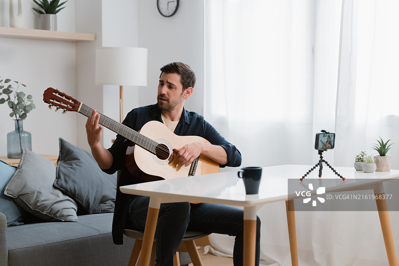 音乐家在家用智能手机录制原声吉他音乐视频图片素材