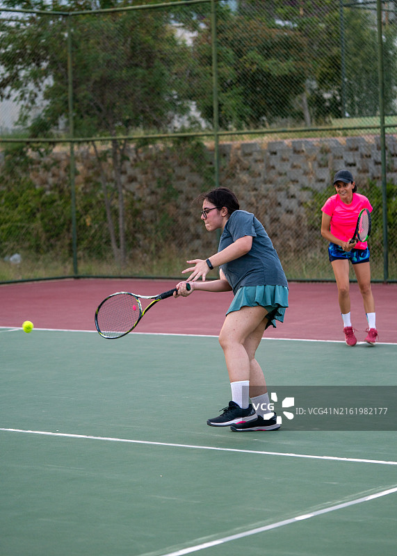 网球少女正手击球，背景是硬地球场上的女子网球运动员图片素材