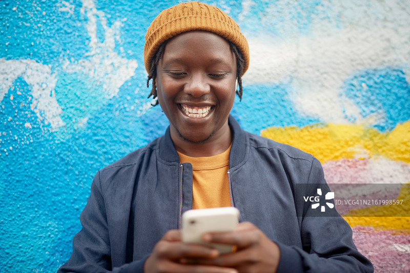 黑人男子在涂鸦墙前使用手机进行社交图片素材