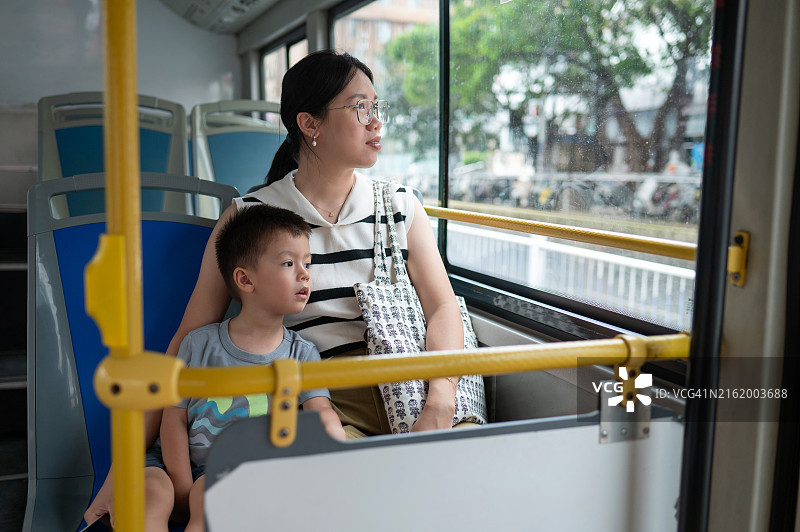 母子在城市环境中看向巴士的窗外图片素材