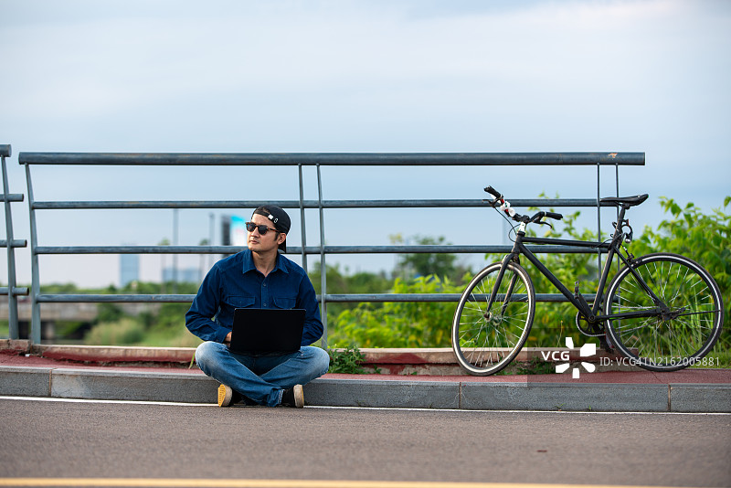 男子坐在地上，面前放着一台笔记本电脑图片素材
