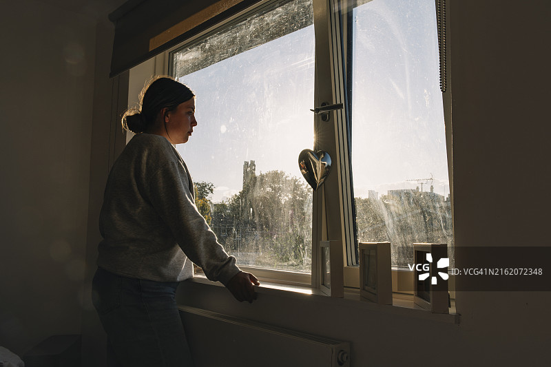 望着卧室窗外的年轻女人——负面情绪图片素材