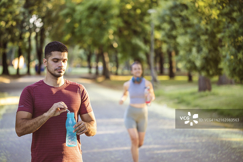 年轻的白人男性运动员在户外活动中休息，补充能量/健康补剂。图片素材