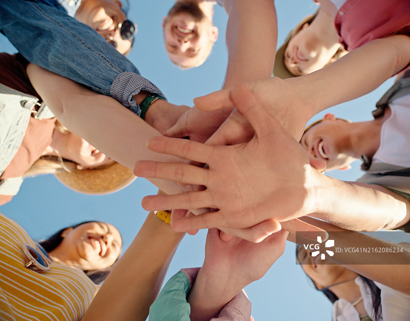 在蓝天下，团结合作的团队将手紧握在一起图片素材