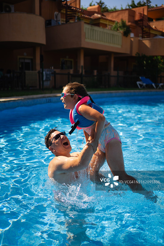 父亲和孩子穿着救生衣在泳池里戏水图片素材
