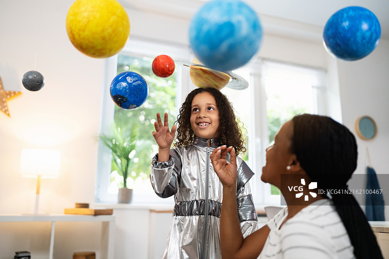 穿着宇航服与黑人母亲一起学习行星的女孩图片素材