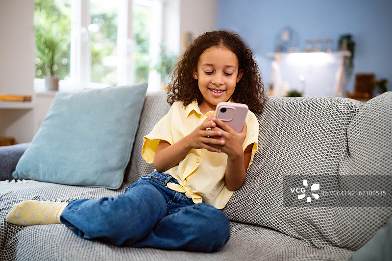 多种族女孩坐在沙发上使用手机图片素材