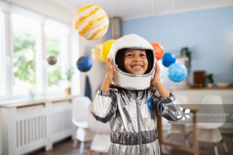 穿着宇航服，被手工制作的行星环绕的多种族女孩肖像图片素材