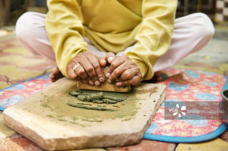 印度乡村老年男人用传统石磨研磨草药图片素材