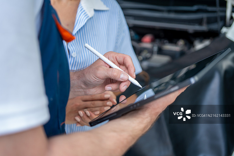 汽车修理工使用平板电脑向顾客展示问题图片素材