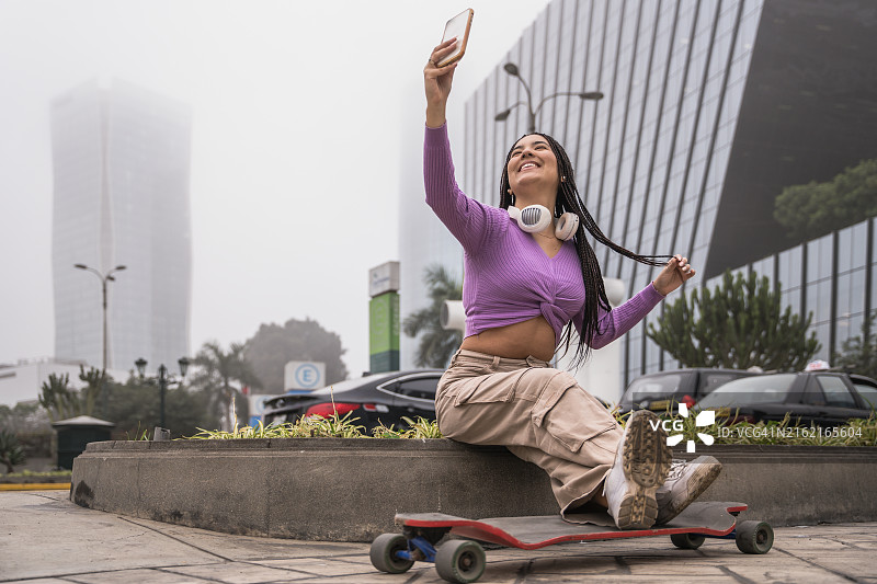 女人和她的滑板在城市街道上自拍图片素材