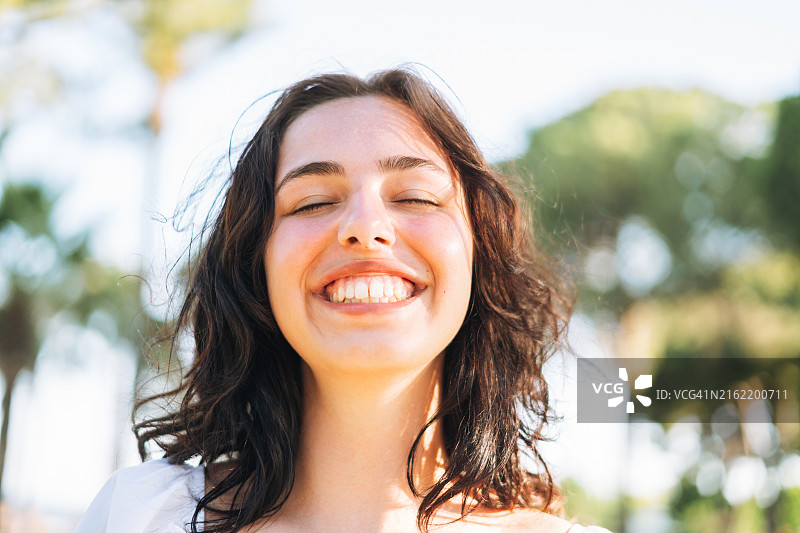 户外闭着眼睛，笑容灿烂的少女特写图片素材