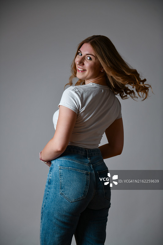 灰色背景上的美丽金发女郎后视图图片素材