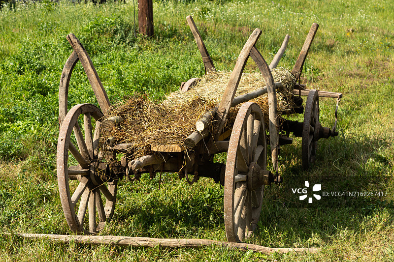 草地上的老式木制干草车轮图片素材