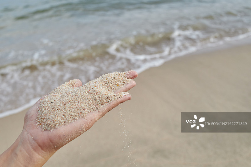 女子在沙滩上手持沙子图片素材