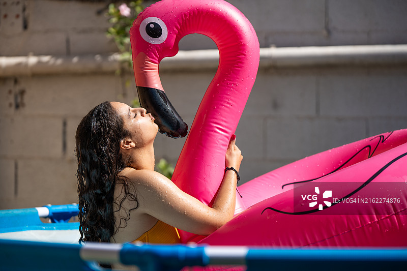 女人亲吻粉色火烈鸟泳圈图片素材