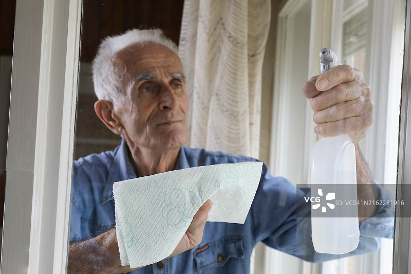 老人用喷雾瓶和抹布清洁窗户图片素材