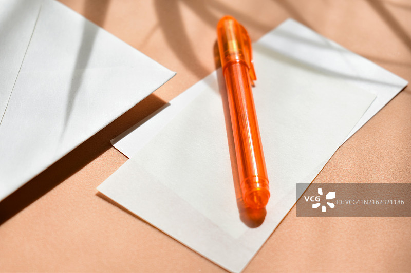 橙色背景下的纸张、信封和铅笔的高角度视图图片素材