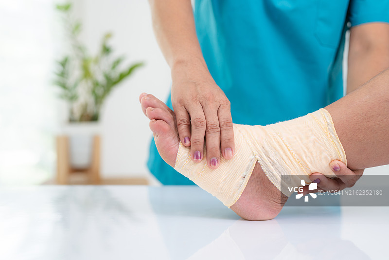 穿白大褂的骨科医生或外科医生检查足痛患者的特写。拇外翻或拇囊炎伴转移性跖痛。骨科病房。图片素材