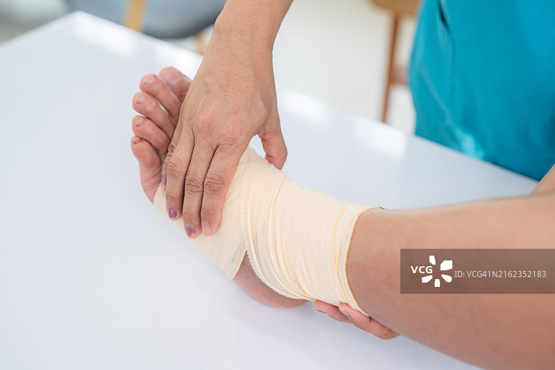 穿白大褂的骨科医生或外科医生检查足痛患者的特写。拇外翻或拇囊炎伴转移性跖痛。骨科病房。图片素材