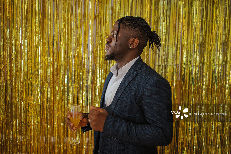 穿着燕尾服，在毕业舞会上拿着香槟酒杯的优雅男士图片素材
