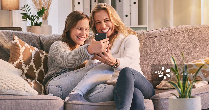 自拍，快乐和母亲与孩子在客厅里进行流媒体、社交媒体和更新。家庭，少女和妇女在家中进行连接、模因和在线滚动和头像图片素材