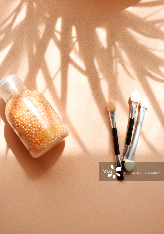橙色背景上的化妆瓶和化妆刷图片素材