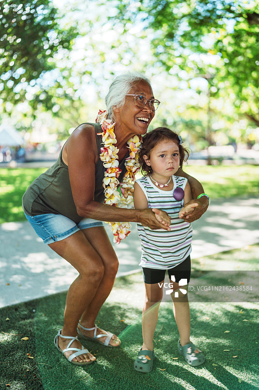 在公园参加草裙舞课程时，夏威夷老妇人帮助孙女图片素材