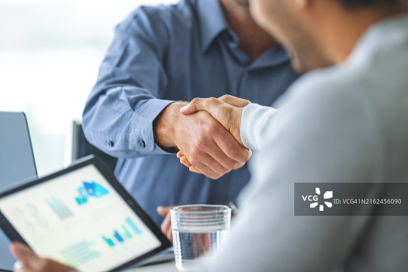 两位商人在会议室里使用平板电脑和笔记本电脑工作图片素材