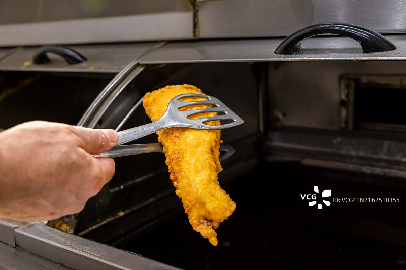 工人捡起一块刚炸好的鱼图片素材