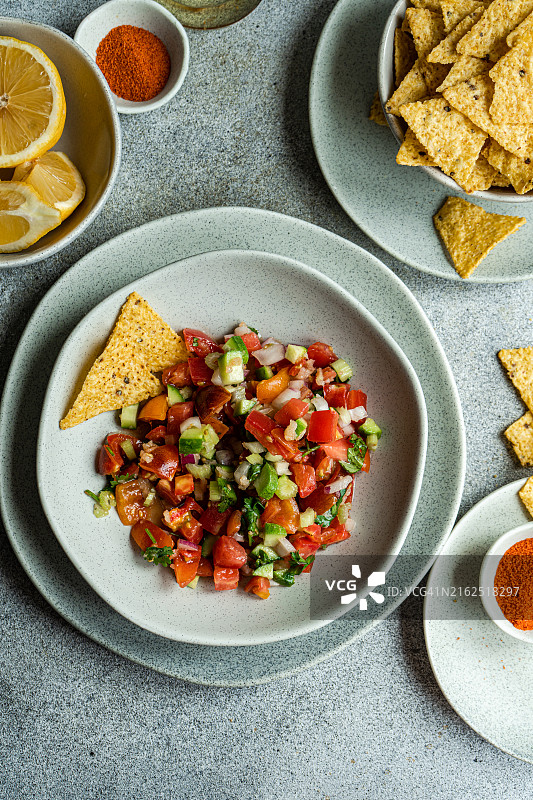 俯视角度：一碗传统墨西哥Pico de Gallo莎莎酱，配玉米片和新鲜柠檬图片素材