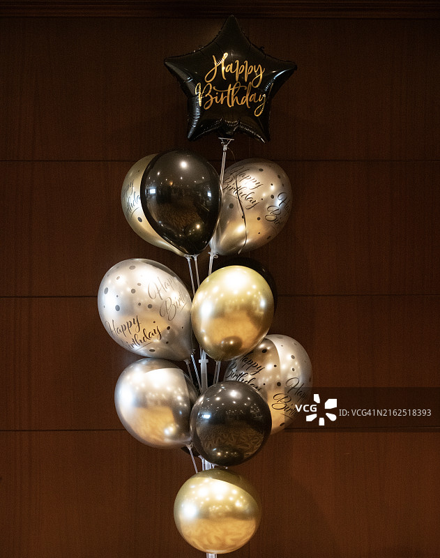 木墙前方的黑色和银色生日气球特写图片素材