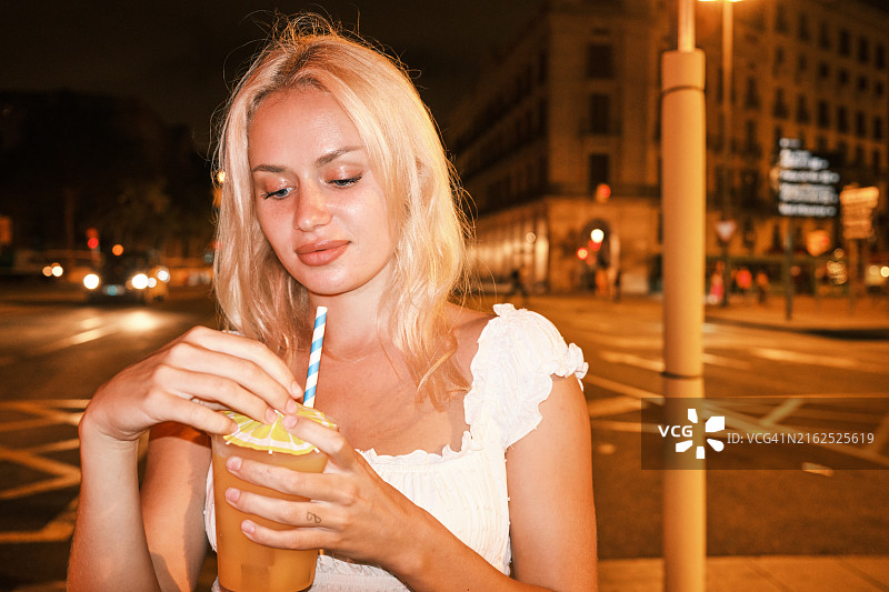 喝着吸管饮料的金发女子图片素材