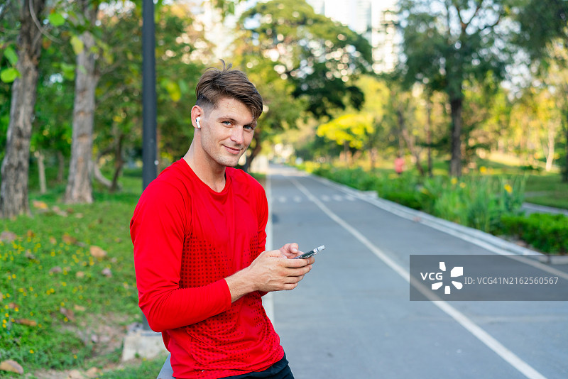 在公园里戴着耳机使用智能手机的男人图片素材