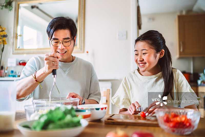 年轻的亚洲父亲和十几岁的女儿在家里一起准备健康的饭菜图片素材