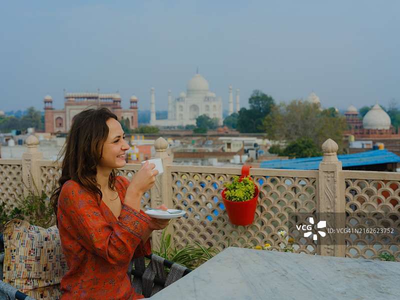 在阳台上眺望泰姬陵并喝茶的女人图片素材