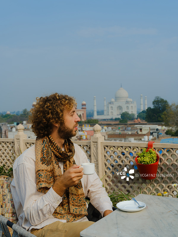 男人在印度旅行期间在阳台上喝茶，俯瞰泰姬陵图片素材