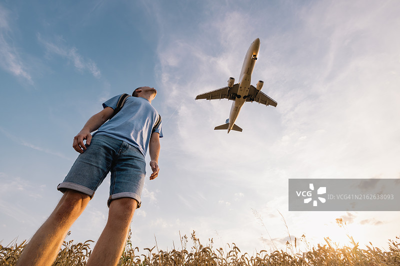 男子抬头看飞机降落图片素材