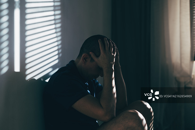 悲伤的男人手托着脸坐着图片素材