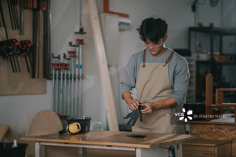 中国年轻人在木工房戴手套准备工作图片素材