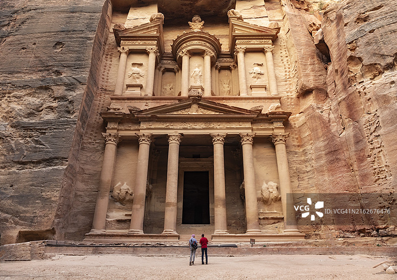 两名游客站在约旦佩特拉的卡兹尼神殿图片素材