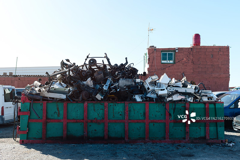 装满垃圾的垃圾箱位于砖砌建筑前图片素材